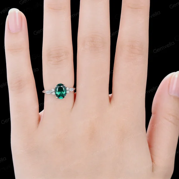 Lifestyle shot of a woman wearing the oval green emerald and moissanite engagement ring, highlighting the elegant look on the finger.
