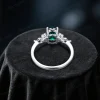 Top down close-up view of the center oval green emerald stone surrounded by a halo of marquise cut moissanite stones.