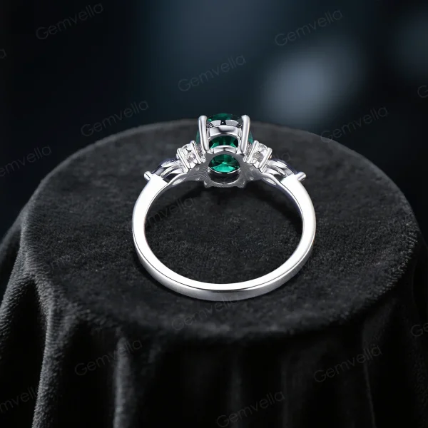 Top down close-up view of the center oval green emerald stone surrounded by a halo of marquise cut moissanite stones.