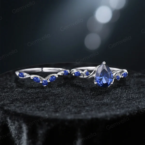 Flat lay photography of the vintage pear cut blue sapphire twig engagement ring and matching vine band arranged on a soft neutral background to showcase the full design.