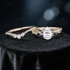 Flat lay photography of the nature inspired moissanite engagement ring and wedding band set separated to show the intricate leaf details and the pear shaped diamond alternative stone.