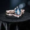 Angled view highlighting the depth of the pear shaped London Blue Topaz stone and the textured branch design of the bridal ring set.