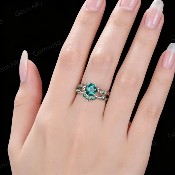Lifestyle close-up of a woman's hand wearing the vintage 1.2ct round cut green emerald ring, demonstrating the dainty stackable vine leaf design on the finger.