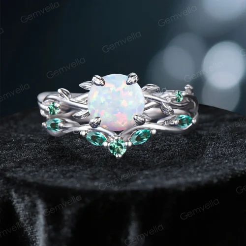 Front view of a vintage 1.2ct round cut opal engagement ring set featuring green emerald accents and a twisting vine leaf design.
