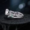 Side profile showing the twisting vine leaf band with green emerald accents and the opal center stone setting.