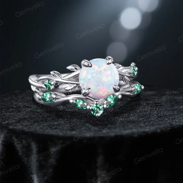 Angled view highlighting the opal center stone sparkle and green emerald accents on the nature inspired vine leaf band.