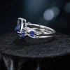 Side profile of the nature-inspired engagement ring highlighting the intricate twig vine detailing along the band and the elegant setting of the pear cut blue sapphire.