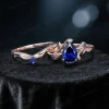 Flat lay photography of the complete nature inspired blue sapphire bridal set showing the engagement ring paired with the matching leaf motif wedding band