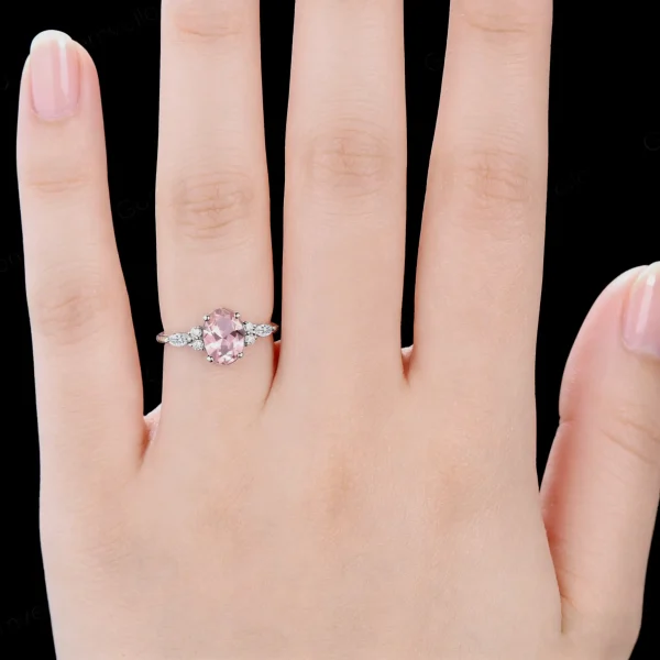 Woman wearing 1.5ct oval pink sapphire and marquise moissanite promise ring on finger for size reference