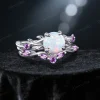 45-degree angle shot revealing the three-dimensional depth of the leaf and vine motif, the iridescent flashes of the central Opal, and the rich violet hue of the surrounding Amethyst accents.