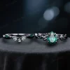 Flat lay photography of the black gold emerald and moss agate ring set, showing the complete gothic bridal jewelry pair with twig vine design details.