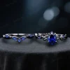 Flat lay photography of the black gold blue sapphire ring set, showing the complete gothic bridal jewelry pair with twig vine design details.