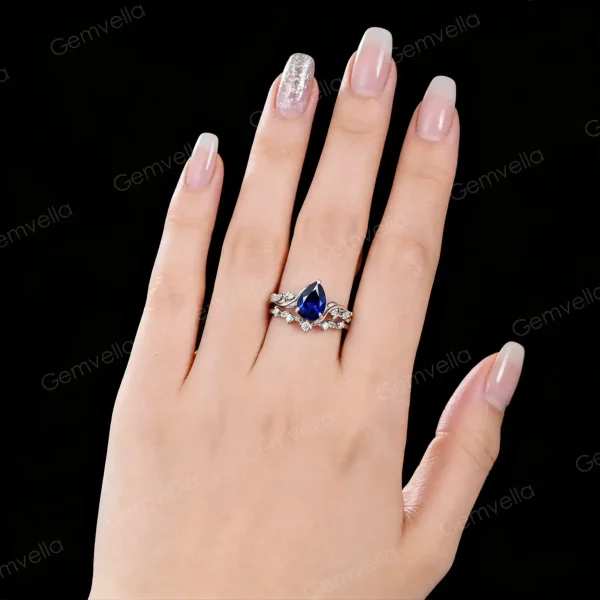 Lifestyle image of a woman's hand wearing the 1.25ct pear cut blue sapphire ring, highlighting the sterling silver nature twig design as an anniversary or engagement gift.
