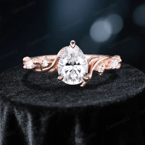 Close-up front view of the 1.25ct pear cut moissanite center engagement ring, featuring intricate leaf vine and branch detailing around the solitaire setting