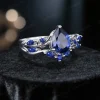 Angled perspective of the vintage blue sapphire engagement ring showcasing the pear cut center stone and the delicate twig vine metalwork wrapping around the band.