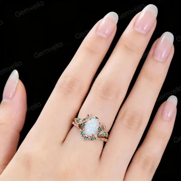 Close-up of 10K rose gold leaf vine branch engagement ring worn on hand, showcasing the nature inspired 1.5ct oval opal and emerald bridal set in real-life wear with detailed leaf vine design