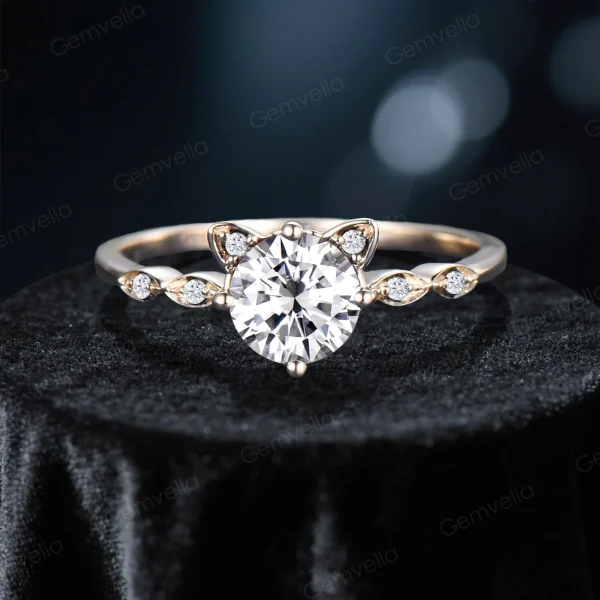 Detailed front view of the main cat-themed engagement ring, focusing on the round-cut moissanite center stone, the cat ear-shaped prongs, and the sparkling side stones in 14K yellow gold.