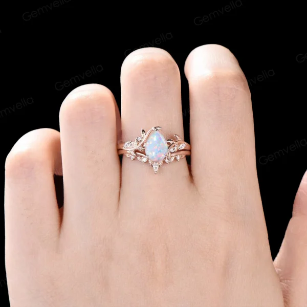 Lifestyle image of a woman's hand wearing the 1.25ct pear cut white opal ring set, showing how the 14k rose gold leaf vine bypass bands sit elegantly on the finger.