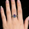 A model's hand wearing the vintage alexandrite engagement ring and emerald twig vine band together.