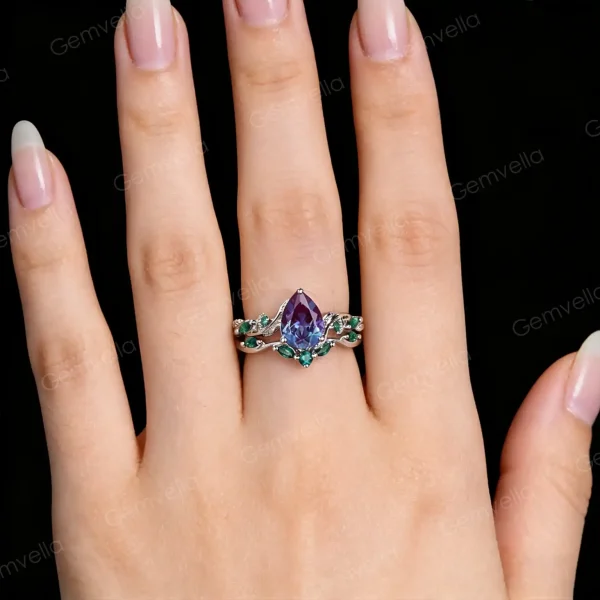 A model's hand wearing the vintage alexandrite engagement ring and emerald twig vine band together.
