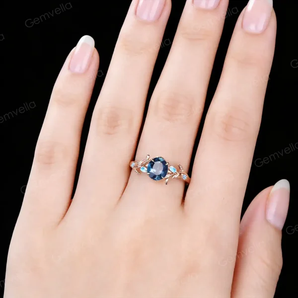 Close-up of a woman's hand wearing the 1ct London Blue Topaz and Moonstone ring, showing how the vintage rose gold engagement ring looks on finger with natural lighting.