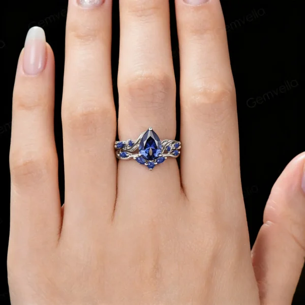 Model hand wearing the antique style pear cut blue sapphire engagement ring and matching vine band, showing how the nature-inspired set looks when worn.