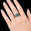 Close up shot of the black gold 1.25ct pear cut emerald and moss agate ring set worn on a woman's hand, displaying how the gothic twig vine engagement and wedding rings look when worn.