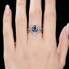 Lifestyle shot of a woman's hand wearing the unique cat themed engagement ring and wedding band set, demonstrating the fit and scale of the round alexandrite and moissanite jewelry on the finger.