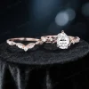 Flat lay image of the complete nature inspired moissanite engagement ring set, including the 1.25ct pear cut center ring and matching leaf vine branch twist band wedding ring