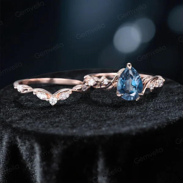 Flat lay photography of the two piece wedding set displaying the pear cut blue topaz engagement ring and matching nature inspired vine band.