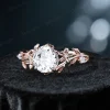 Angled view of a vintage round cut moissanite engagement ring, showing the relationship between the center stone and the 14k gold setting with its nature-inspired leaf vine branch details from a diagonal perspective.