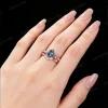 Lifestyle image of a woman wearing the 1.25ct pear cut London Blue Topaz and nature inspired leaf vine wedding ring set on her finger.