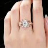 Lifestyle photo of a woman's hand wearing a 1.25ct pear moissanite bypass engagement ring in 14K rose gold, showing how the leaf vine branch design looks when worn, with natural lighting highlighting the moissanite sparkle and nature-inspired bridal jewelry aesthetic.