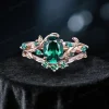 Front view of 1.5ct oval emerald bridal ring set in 10K rose gold, featuring nature inspired leaf vine branch design and vintage detailing
