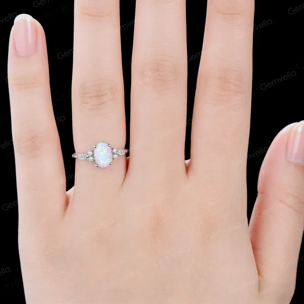 A woman's hand modeling the elegant 1.5ct Oval Opal and Marquise Moissanite ring, showcasing the unique celestial style as an anniversary or engagement gift for her.