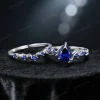 Flat lay image of the 1.25ct pear-cut blue sapphire engagement ring and its matching nature-inspired twig vine wedding band, displayed together on a neutral background to show the complete set and their complementary designs.