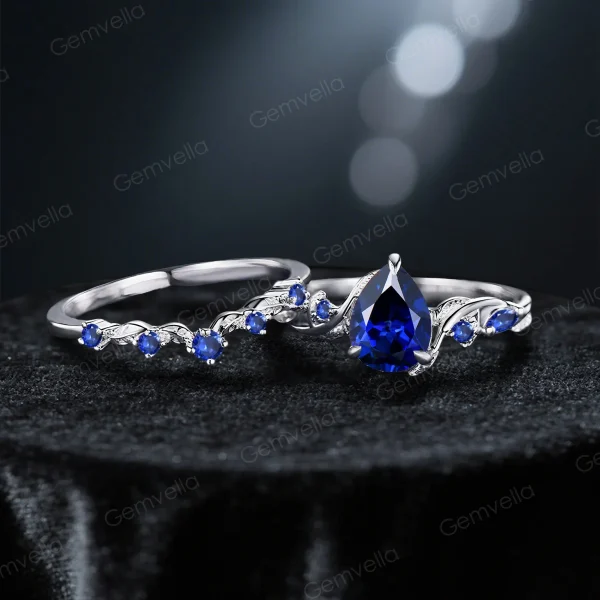 Flat lay image of the 1.25ct pear-cut blue sapphire engagement ring and its matching nature-inspired twig vine wedding band, displayed together on a neutral background to show the complete set and their complementary designs.