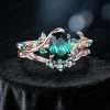 Angled view of 1.5ct oval emerald engagement ring set in 10K rose gold, showcasing the nature inspired leaf vine branch design and vintage style