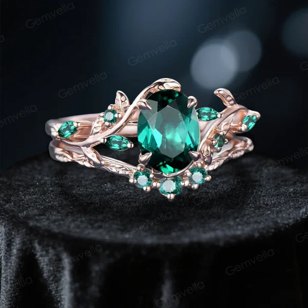 Angled view of 1.5ct oval emerald engagement ring set in 10K rose gold, showcasing the nature inspired leaf vine branch design and vintage style
