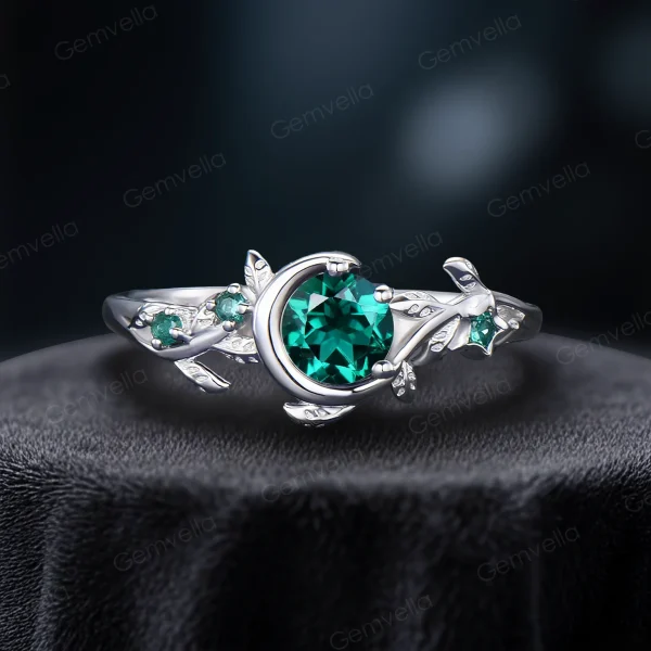 A bright and shiny 925 sterling silver emerald ring, highlighting the contrast between the silver metal and the deep green round cut stone with nature-inspired leaf and celestial details.