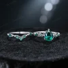 A laydown photograph displaying the full width and detailed design of the vintage pear cut emerald engagement ring set, highlighting its antique noble bridal jewelry elements.