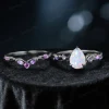 Flat lay of nature-inspired engagement ring set with 1.25ct pear-cut opal in black gold, elegant twig vine detail