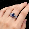 A woman's hand wearing the 1.25ct pear-cut blue sapphire engagement ring and matching sterling silver twig vine wedding band, showing how the nature-inspired set looks when worn, with the leaf details wrapping around the finger.