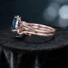 Side angle of the nature-inspired bridal set, showcasing the rose gold band's thickness, the layered design of the engagement ring and wedding band, and the setting of the blue topaz and sapphires.