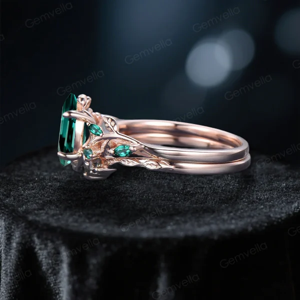 Side profile of 10K rose gold emerald ring set showing the leaf vine branch band design and 1.5ct oval emerald stone setting