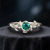Side view of a classic yellow gold engagement ring showcasing a vibrant 1ct round green emerald, surrounded by delicate leaf details and a vintage moon and star design.