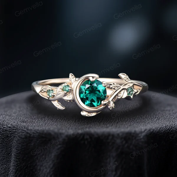 Side view of a classic yellow gold engagement ring showcasing a vibrant 1ct round green emerald, surrounded by delicate leaf details and a vintage moon and star design.