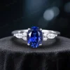 Front view of an elegant 1.5 carat oval blue sapphire engagement ring featuring marquise cut moissanite accents on a silver band.