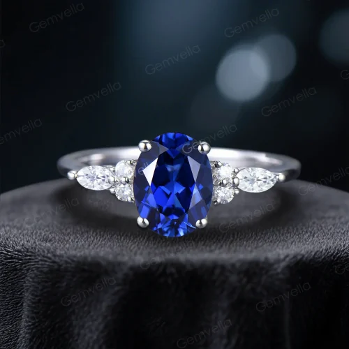 Front view of an elegant 1.5 carat oval blue sapphire engagement ring featuring marquise cut moissanite accents on a silver band.